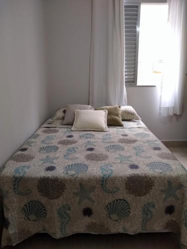 a bed in a bedroom with a blanket on it at Apartamento no Guarujá in Guarujá