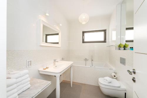 a white bathroom with a sink and a tub and a toilet at The View Luxury Residence with Pool in Zadar