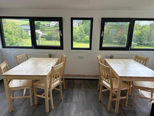 two tables and chairs in a room with windows at VilaEva Adršpach Broumovsko in Ruprechtice