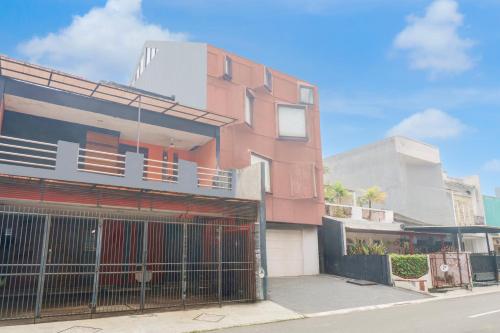 a pink building with a gate on the side of a street at Hotel O Pondok Indah Near Gandaria City Formerly Odori Residence in Jakarta