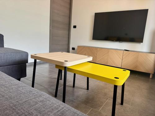 a yellow table and bench in a room with a tv at La Gare Apartments - Zerbion in Châtillon