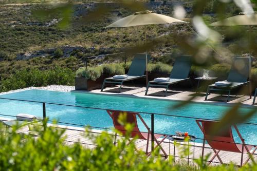 a pool with three chairs and a table and an umbrella at Dimora degli Ulivi 10 Emma Villas in Noto