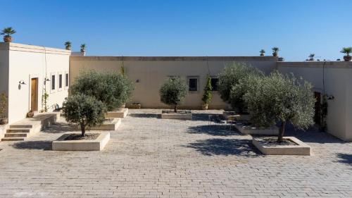 a courtyard with trees in planters in front of a building at Dimora degli Ulivi 10 Emma Villas in Noto