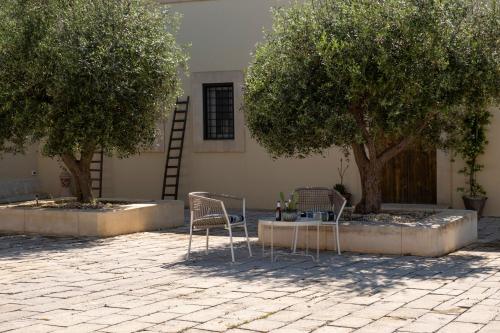 two chairs and a table in a courtyard with two trees at Dimora degli Ulivi 10 Emma Villas in Noto