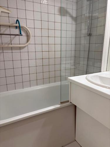 une salle de bain carrelée blanche avec une douche et un lavabo dans l'établissement St Cyprien golf appart avec terrasse et piscine, à Saint-Cyprien