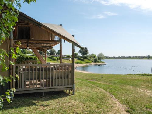 a building with a fence next to a body of water at Resort Rhederlaagse Meren in Lathum