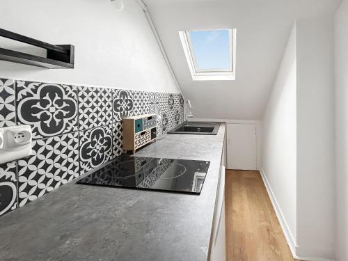 - une cuisine avec du carrelage noir et blanc sur le mur dans l'établissement Douillet studio avec Wi-Fi, proche Transports, à Tours