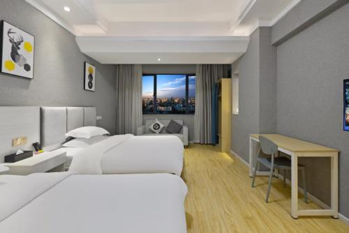 a hotel room with two beds and a desk at Home Inn Paibaiyun Hotel Chengdu Tianyu Road Subway Station Branch in Chengdu