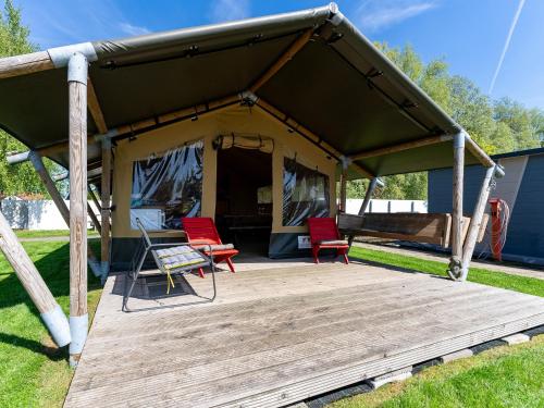 a tent with two red chairs and a wooden deck at Safaritent Heeg 4 persoons in Heeg