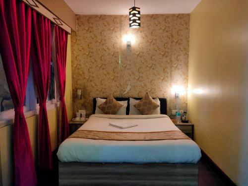 a bedroom with a large bed with red curtains at Bon The Rink Heritage in Darjeeling