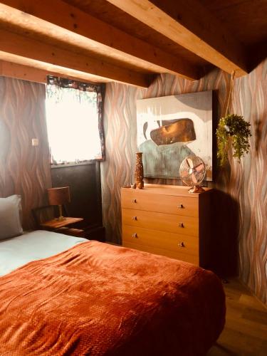 a bedroom with a bed and a dresser and a window at Retraitre bij de brug in Zuidveld