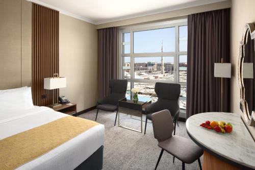 a hotel room with a bed and a desk and a table at Anwar Al Madinah Mövenpick in Al Madinah