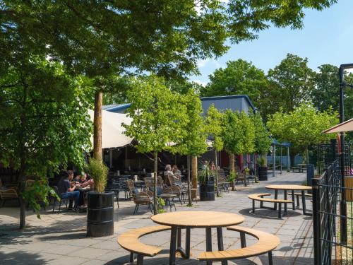 a patio with tables and chairs and people sitting at tables at Resort Rhederlaagse Meren in Lathum