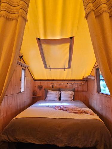 a bedroom with a large bed with a yellow ceiling at Quiétude & Nature in Le Boupère