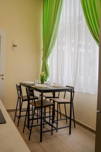 a dining room table with chairs and a green curtain at Luxury Acclavio Apartments in Taranto