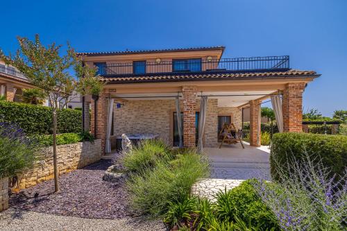 a brick house with a balcony on top of it at Villa Nathalie - Linardici, Krk in Linardići