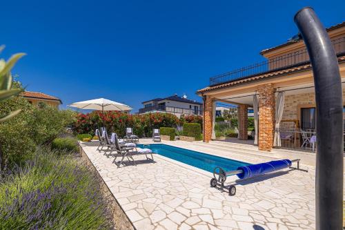 a pool with chairs and a water slide next to a house at Villa Nathalie - Linardici, Krk in Linardići