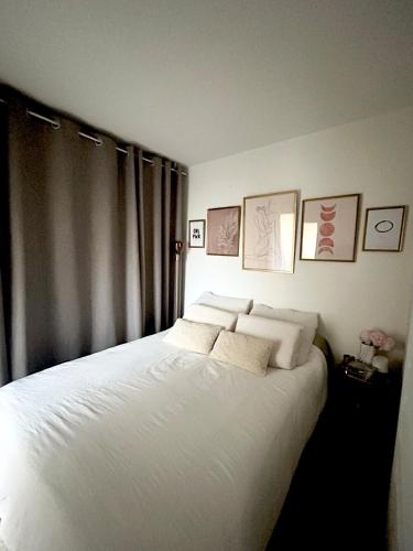 une chambre avec un lit avec des draps blancs et des oreillers dans l'établissement Le Vinci F2 cosy et jardin, à Lattes