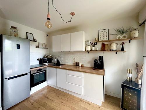 une cuisine avec des armoires blanches et un réfrigérateur blanc dans l'établissement Le Vinci F2 cosy et jardin, à Lattes