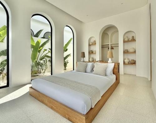a bedroom with a large bed with two windows at Dolce One-Bedroom Villas in Uluwatu