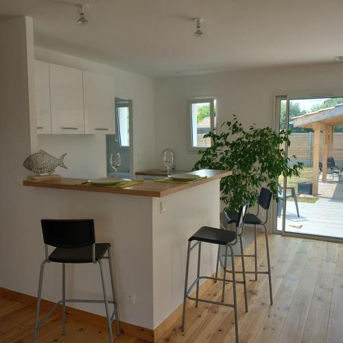 une cuisine avec trois tabourets de bar et un comptoir dans l'établissement CASSY Maison 3 chambres avec jardin, à Lanton