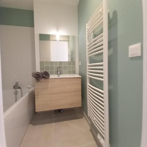 une salle de bain avec un lavabo, une baignoire et un miroir dans l'établissement CASSY Maison 3 chambres avec jardin, à Lanton