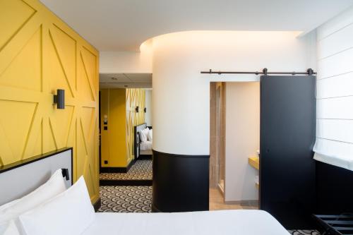 a hotel room with a bed and a yellow wall at Logis Hotel Darcy Dijon Centre in Dijon