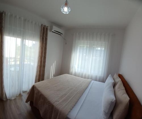 a bedroom with a bed and two windows at L&D Apartments in Ulcinj