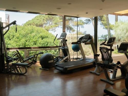 a gym with a bunch of exercise equipment and a large window at Hostal Empúries in L'Escala
