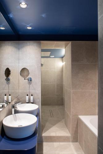 a bathroom with a tub and a sink and a shower at Logis Hotel Darcy Dijon Centre in Dijon