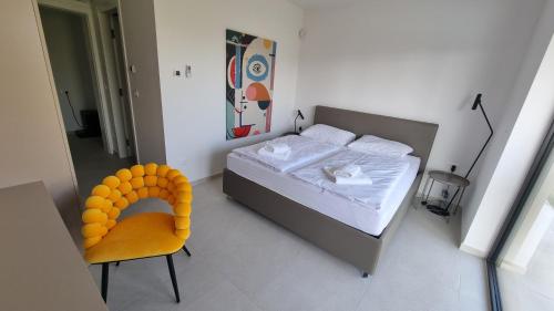 a bedroom with a bed and a yellow chair at Villa Olive in Labinci