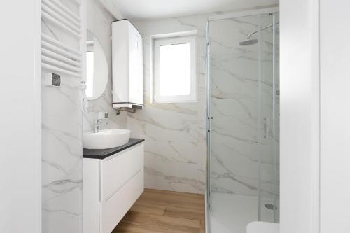 a white bathroom with a sink and a shower at Raduńskie Zacisze in Chmielno