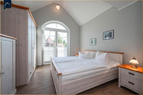 a bedroom with a white bed and an arched window at Koserow Hauptstraße 102 Whg 4 in Ostseebad Koserow