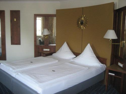 a large white bed with white pillows in a room at Hotel-Gasthof Maisberger in Neufahrn bei Freising