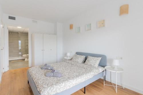 a white bedroom with a bed and a bathroom at Canet Seaview Gem: Pool & Beach Proximity in Canet de Berenguer