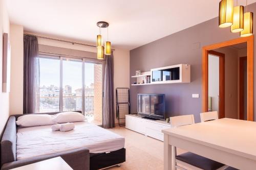 ein Wohnzimmer mit einem Bett und einem Fernseher in der Unterkunft Burriana Beach Retreat: Pool & Comfort in Burriana