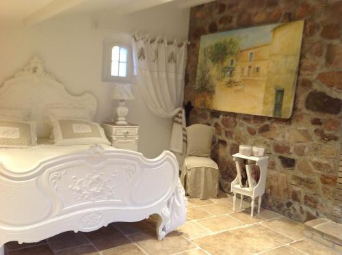 une chambre avec un lit blanc et une chaise dans l'établissement Le mas des peps, à Roquebrune-sur Argens