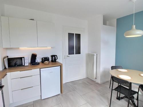 - une cuisine avec des placards blancs, une table, une table et des chaises dans l'établissement Appartement rénové à Colmar avec jardin et terrasse - FR-1-722-11, à Colmar
