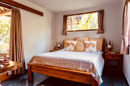 a bedroom with a bed and two windows at Beautiful 3br bohemian villa in Sanur