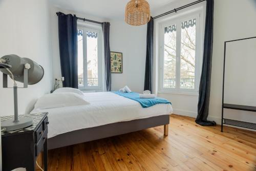 a bedroom with a large bed and two windows at Maison Yasmyn in Villeurbanne