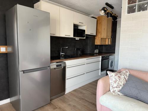 - une cuisine avec un réfrigérateur en acier inoxydable à côté d'un canapé dans l'établissement Appartement Cosy à Carnon, à Mauguio