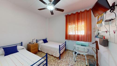 a bedroom with two beds and a table and a ceiling fan at Exclusive Villa in Catadau: Pool & Private Gardens in Catadau