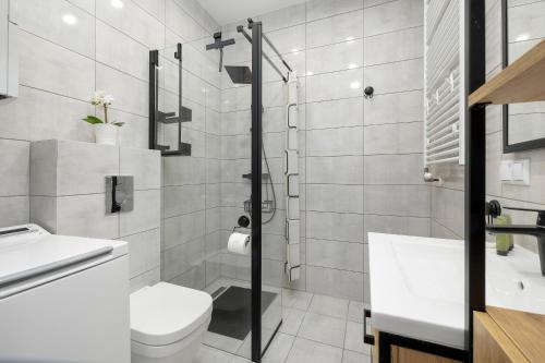 a white bathroom with a toilet and a sink at Paraiso Nadmorskie Apartamenty z Basenem i Parkingiem by Noclegi Renters in Łukęcin