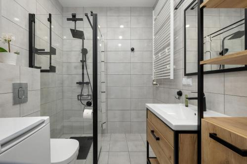 a bathroom with a shower and a toilet and a sink at Paraiso Nadmorskie Apartamenty z Basenem i Parkingiem by Noclegi Renters in Łukęcin