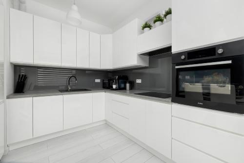 a white kitchen with black and white appliances at Paraiso Nadmorskie Apartamenty z Basenem i Parkingiem by Noclegi Renters in Łukęcin