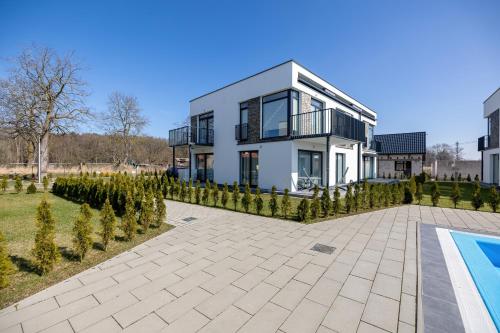 a large white house with a swimming pool in front of it at Paraiso Nadmorskie Apartamenty z Basenem i Parkingiem by Noclegi Renters in Łukęcin