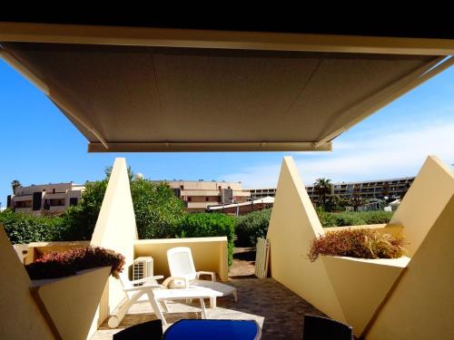 d'une terrasse avec des chaises et des tables blanches sur un balcon. dans l'établissement Appartement CAP FACTORY Héliopolis K1 - Luxe 2 personnes, au Cap d'Agde