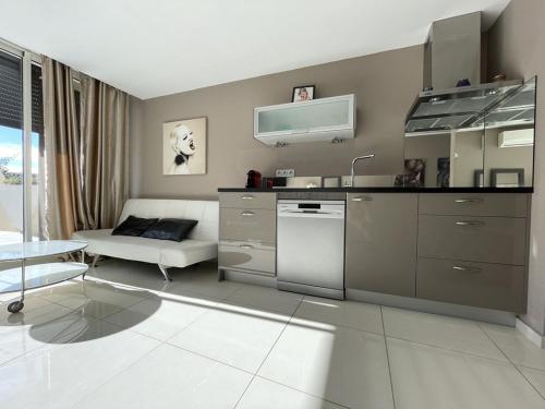 une cuisine avec un évier et un canapé dans une chambre dans l'établissement Appartement KERYLOS Héliopolis K3 - Luxe 2 personnes, au Cap d'Agde