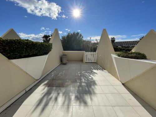 une passerelle avec des murs blancs et le soleil dans le ciel dans l'établissement Appartement KERYLOS Héliopolis K3 - Luxe 2 personnes, au Cap d'Agde