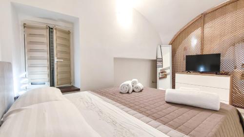 a white bedroom with a large bed with two towels at Il Viandante in Cagliari